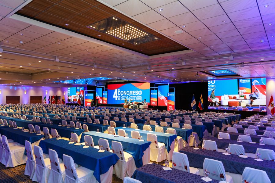 Grand ballroom set for a Latin American shopping-center congress, with blue tables and LED stage
