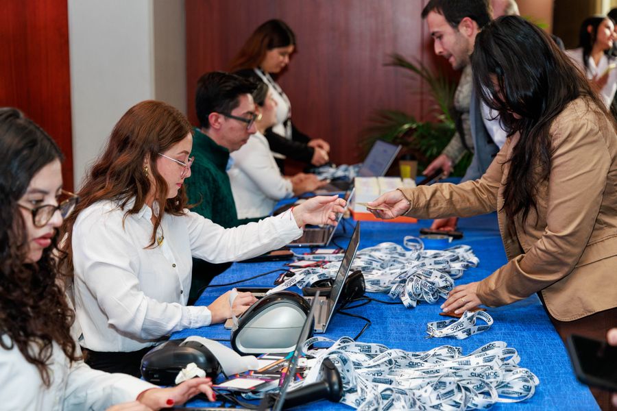 Registration desk staff checking in congress attendees beside piles of branded lanyards