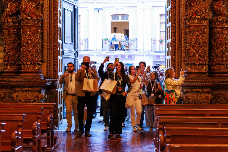 Congress delegates entering a gilded baroque church, filming and photographing its carved golden interior