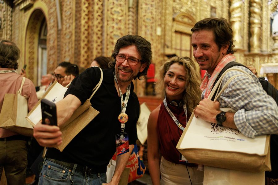 Smiling congress attendees taking a selfie inside an ornate gilded colonial church