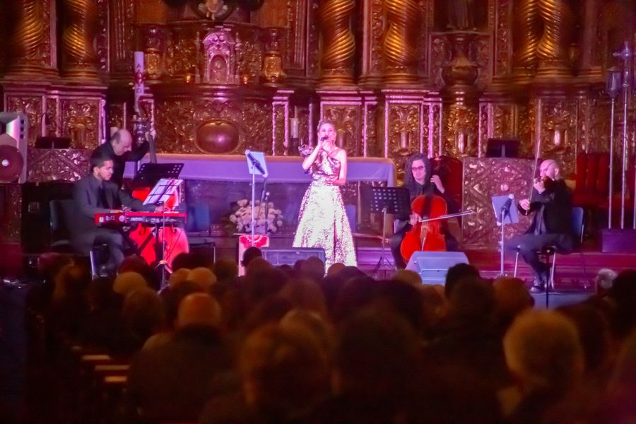 Evening concert with singer in sparkling gown and string ensemble before a golden church altar