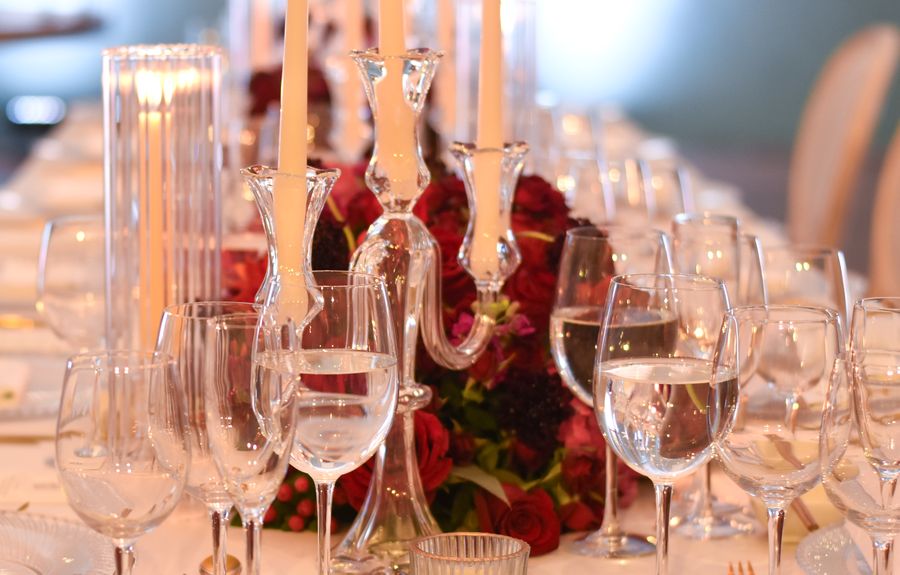 Elegant long dinner table with crystal candelabra, tapered candles, red roses and glassware