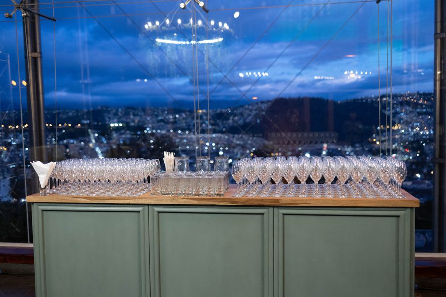 Welcome bar lined with rows of crystal glasses in front of city lights at dusk