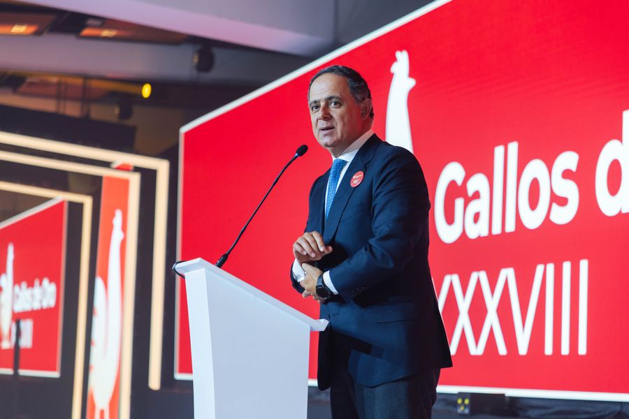 Executive speaking at a white podium in front of a red awards-gala LED backdrop