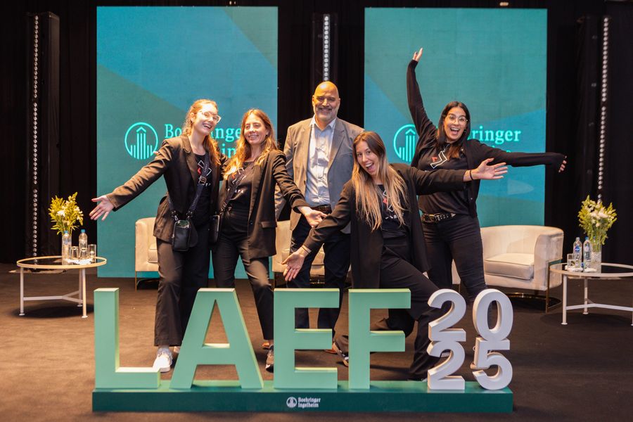 Cheerful event staff posing behind giant 3D letters on a forum stage