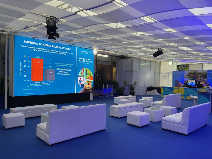 Sponsor lounge with white modular furniture, LED screen and coffee bar under draped ceiling