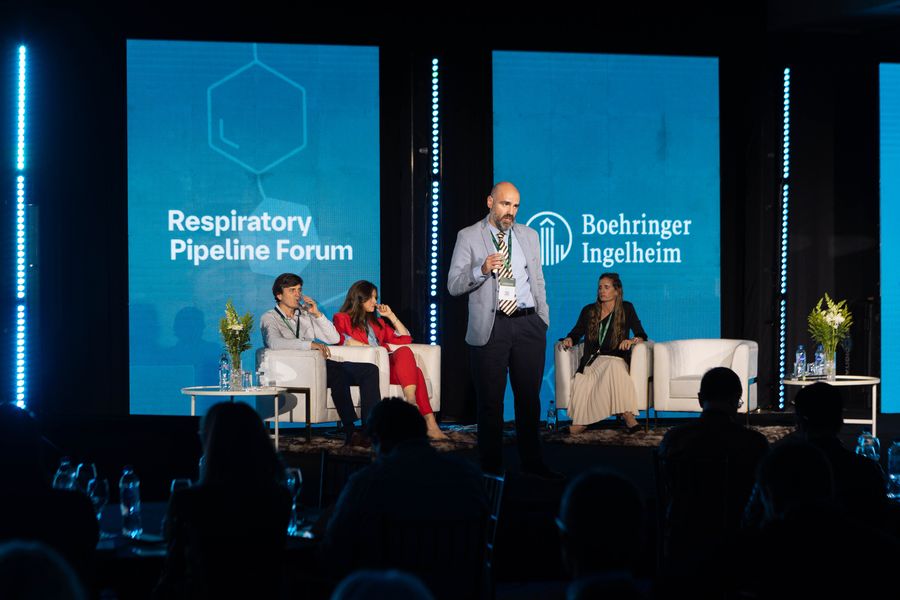 Panel discussion on a corporate congress stage with LED screens, armchairs and audience