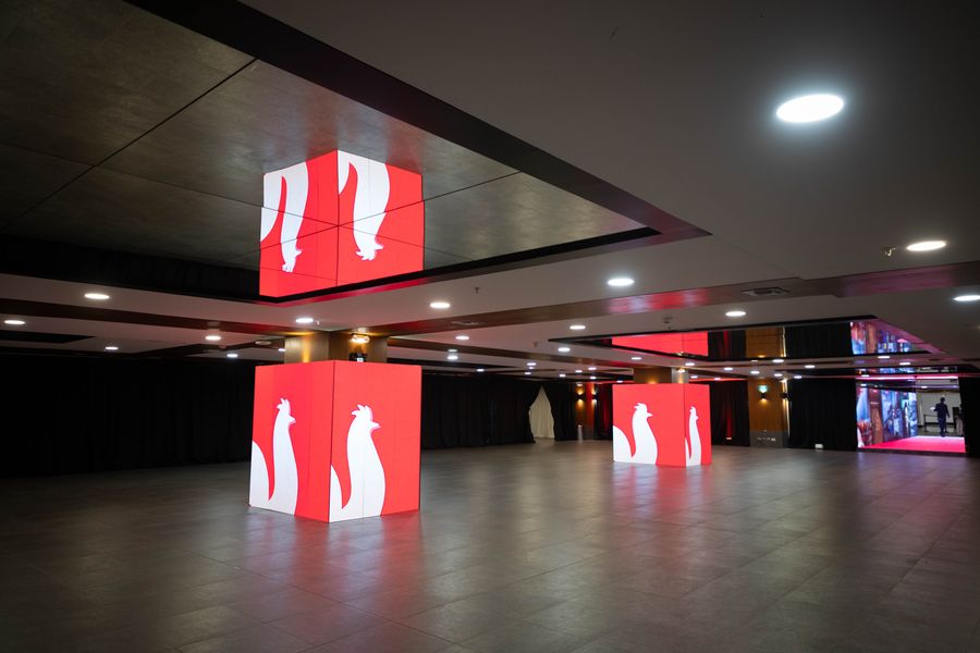 Empty event hall with glowing red LED cube columns and polished floor before guests arrive