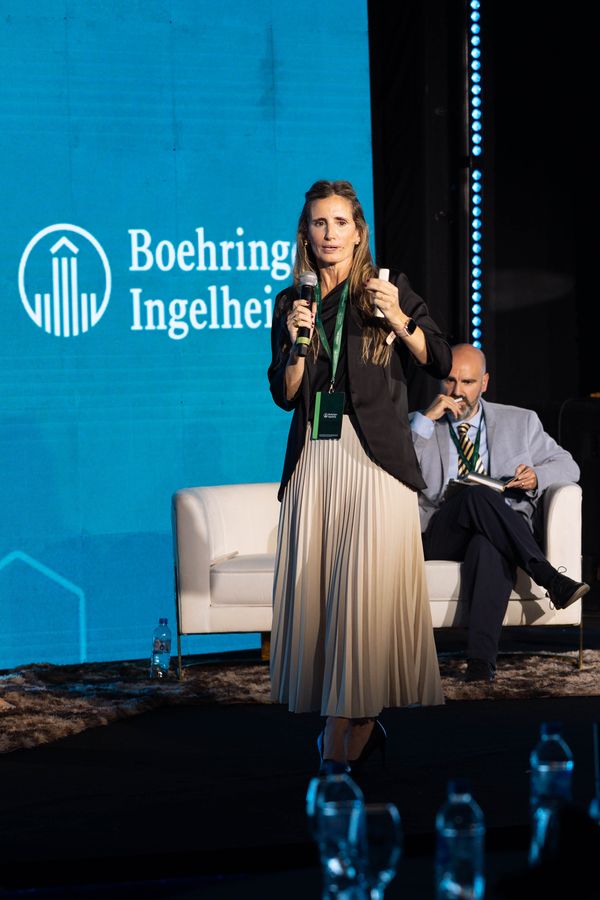 Speaker with microphone presenting on a corporate forum stage with blue LED screen
