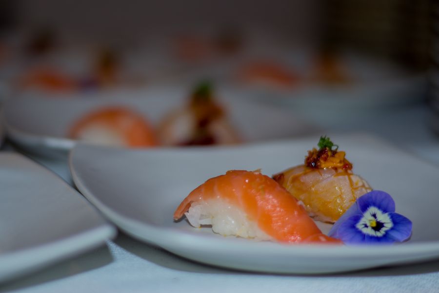 Salmon nigiri and a torched nigiri with crispy topping, garnished with an edible purple viola