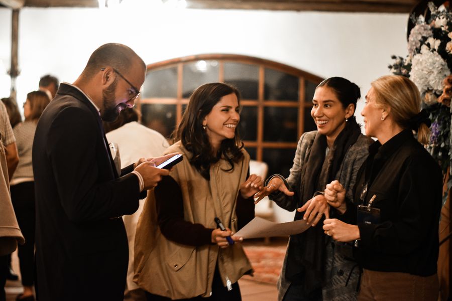 Guests laughing together during an evening team activity in a warm colonial hacienda hall