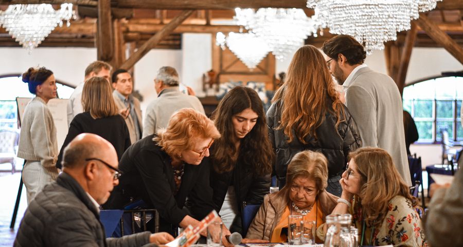 Participants gather around a table for a group challenge beneath crystal chandeliers and wooden beams