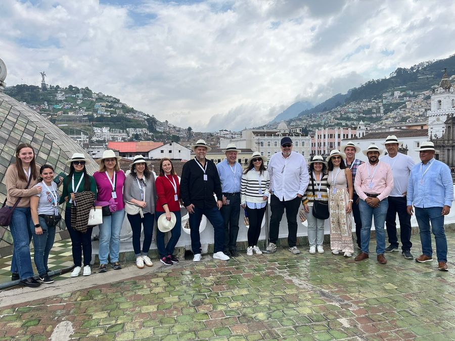 Group in Panama hats on a colonial church rooftop overlooking Quito's hills and old town