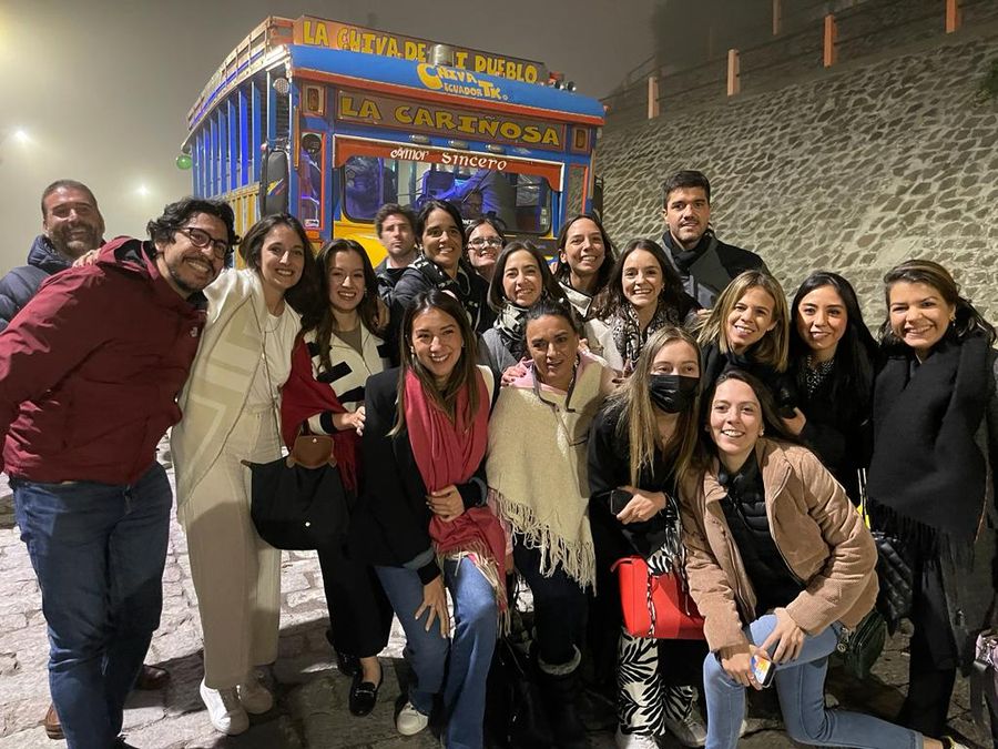 Smiling corporate group posing at night in front of a colorful Ecuadorian party chiva bus