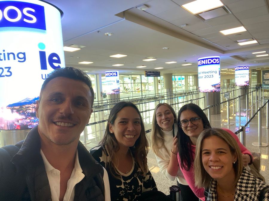 Group selfie at the airport under LED columns welcoming attendees to a regional meeting