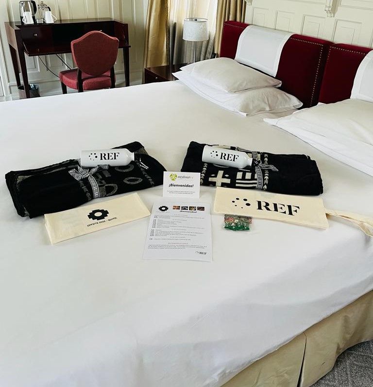 Luxury hotel bed with welcome kit: branded water bottles, blankets, tote bags and welcome letter