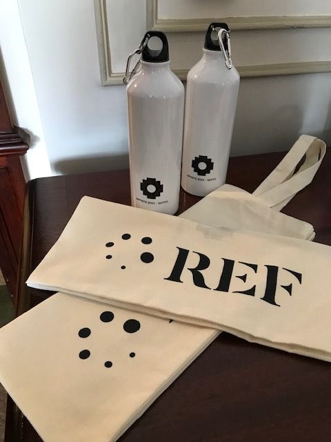 White branded aluminum water bottles and canvas tote bags prepared for a corporate offsite