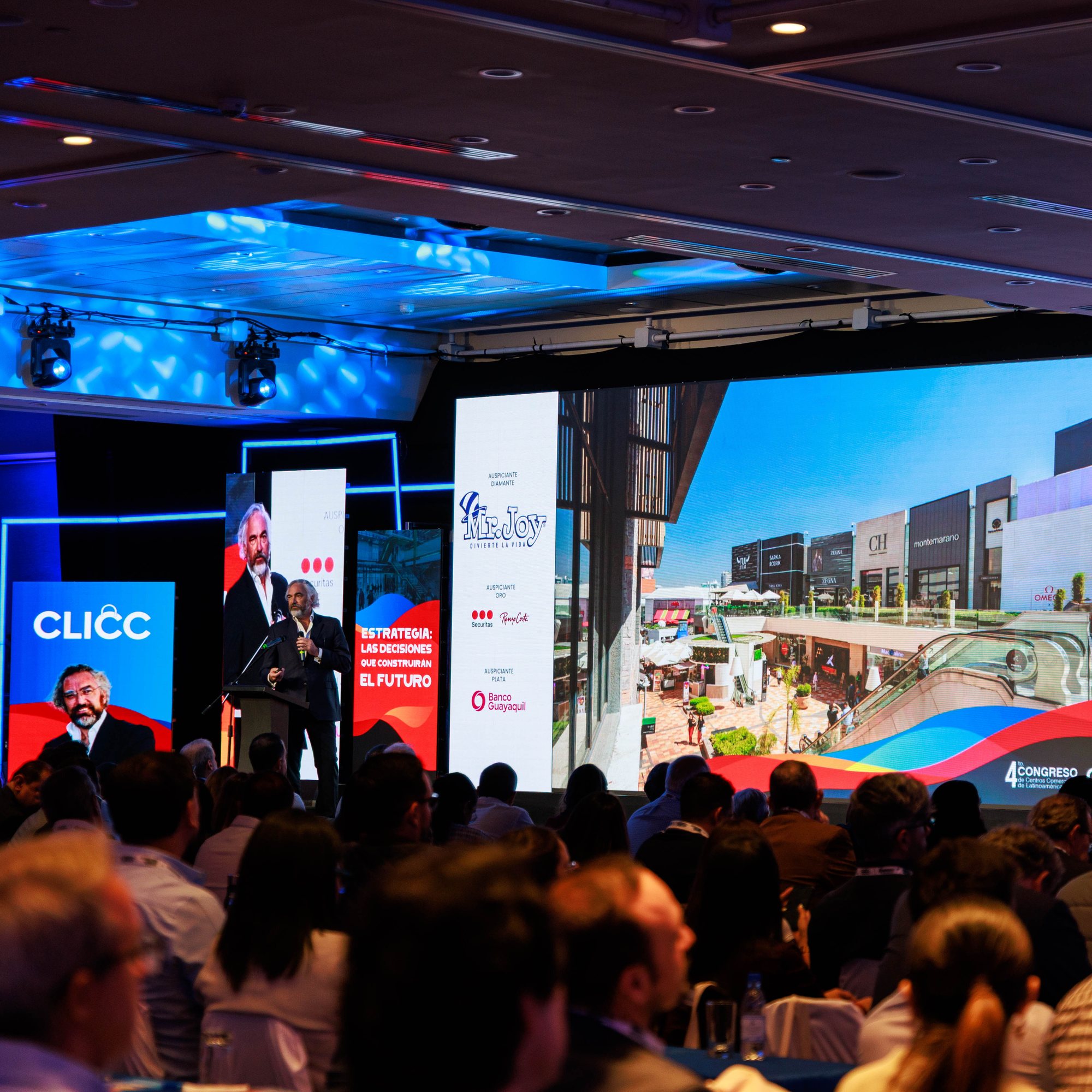 A speaker addressing a packed plenary hall at a business congress