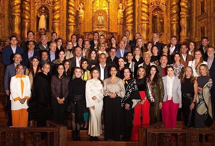 A large corporate group poses before the golden altar of La Compañía church in Quito