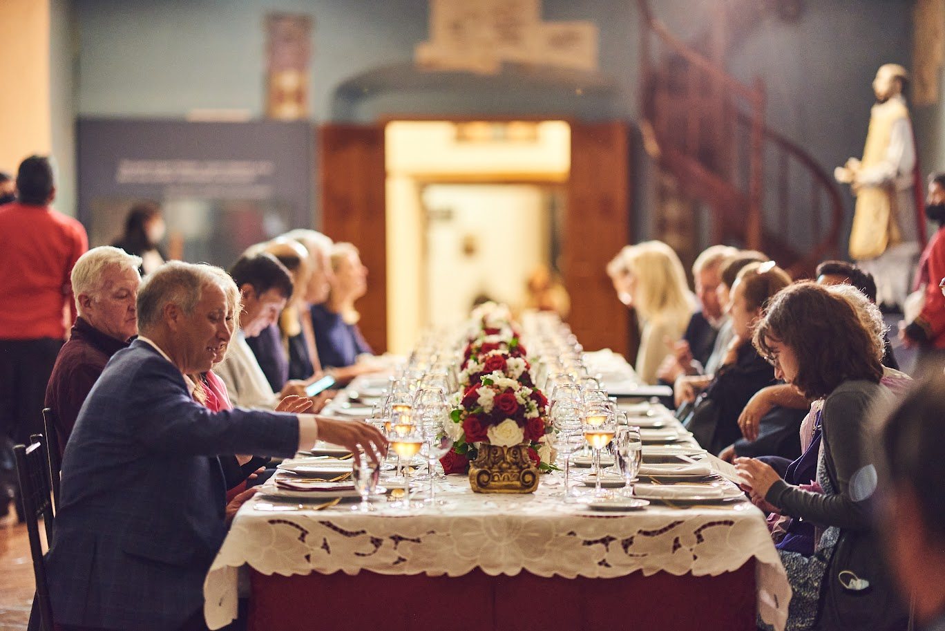 Corporate guests dining at a long banquet table in a colonial hall