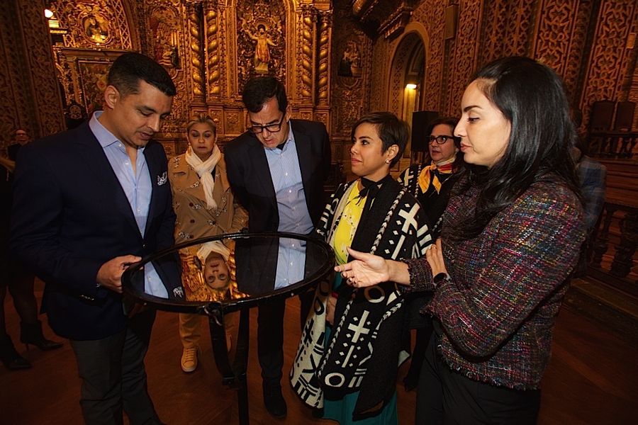 Guests gather around a standing mirror inside the gilded La Compañía church in Quito