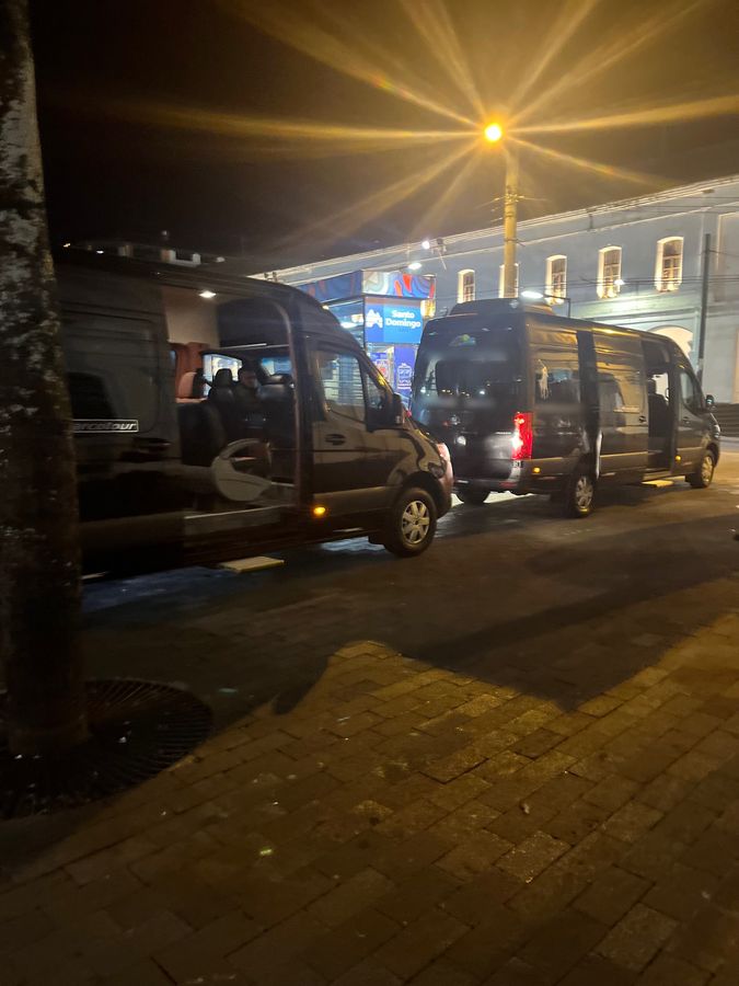 Two private passenger vans lined up at night for a group transfer