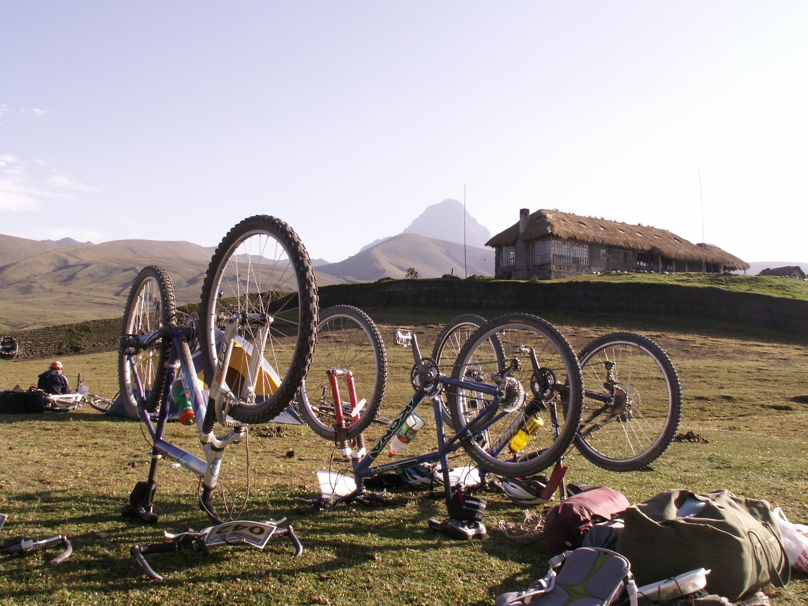 Group mountain bikes resting on the grass at an Andean hacienda below Cotopaxi volcano